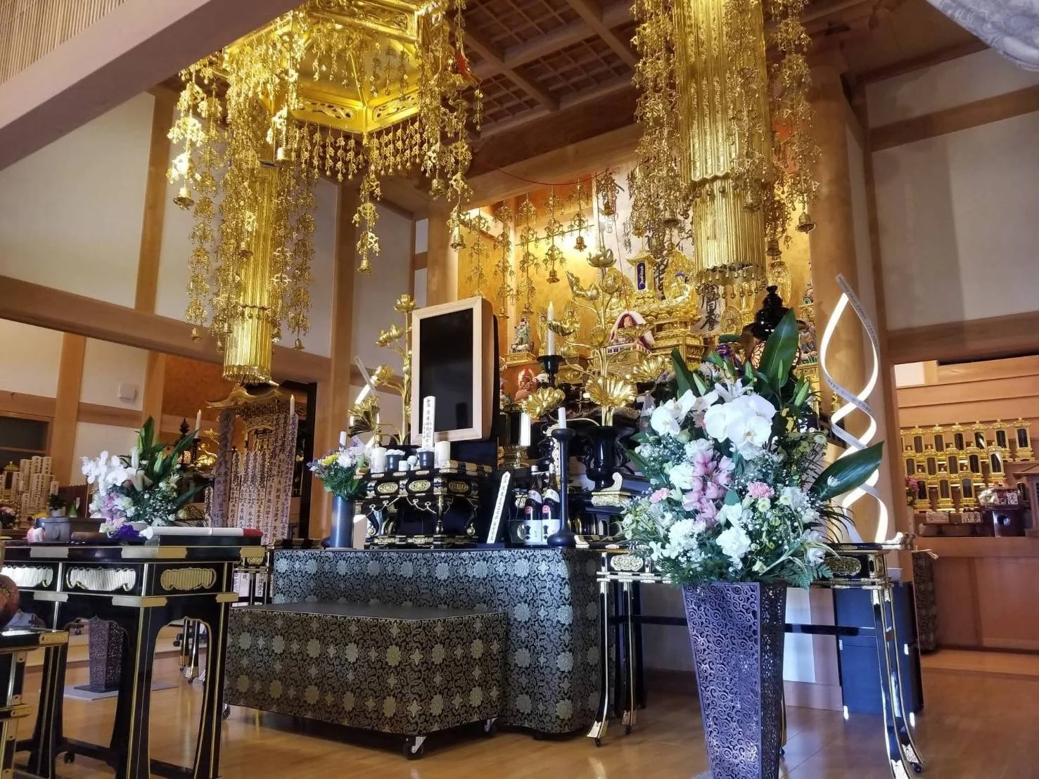 夕方の光に包まれた妙福寺の本堂外観と手前に広がる境内